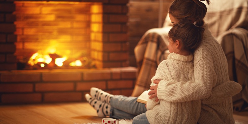 sisters holding each other in front of fireplace.
