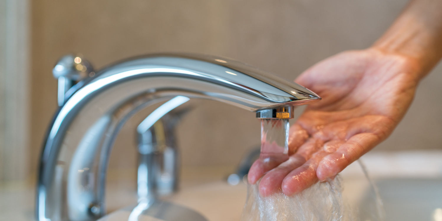 Hand Running under hot water - Tankless Water Heaters: Benefits and Common FAQs